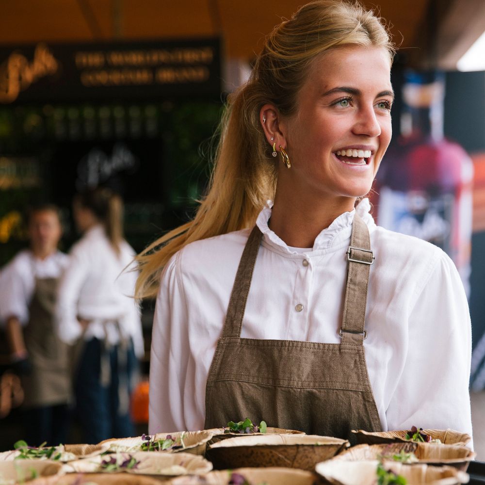 Bediening die lachend een dienblad vasthoudt