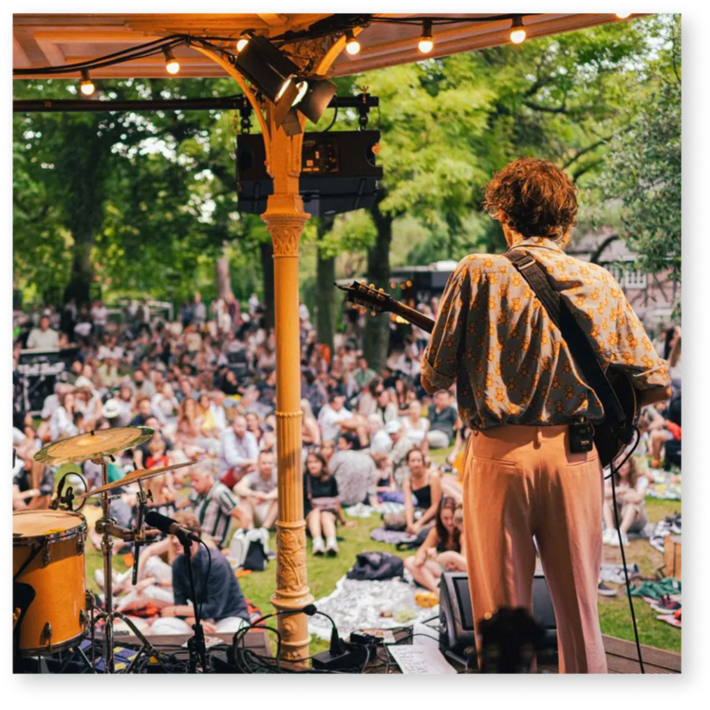Iemand van achteren die gitaar speelt voor heel veel mensen