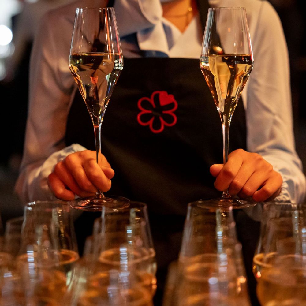 iemand met een michelin sterren schort die 2 glazen champagner vasthoudt